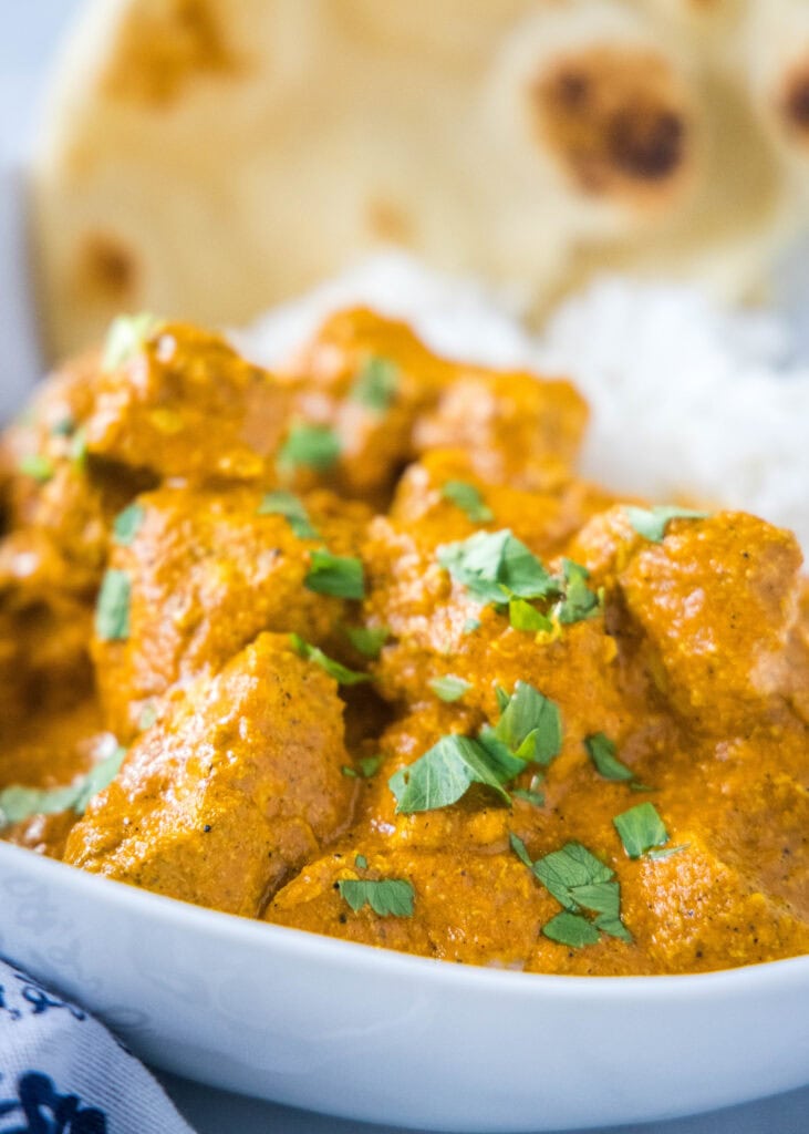 butter chicken curry topped with cilantro in a white bowl
