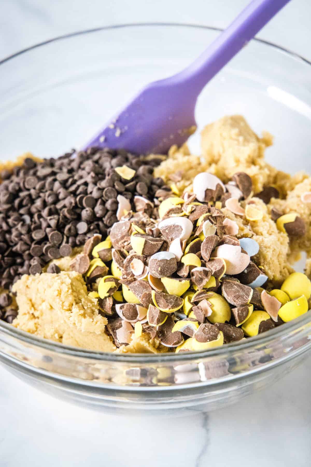 adding chocolate chips and mini eggs to cookie dough