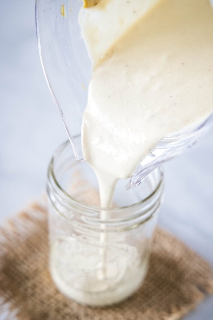 pouring blended caesar dressing into a jar