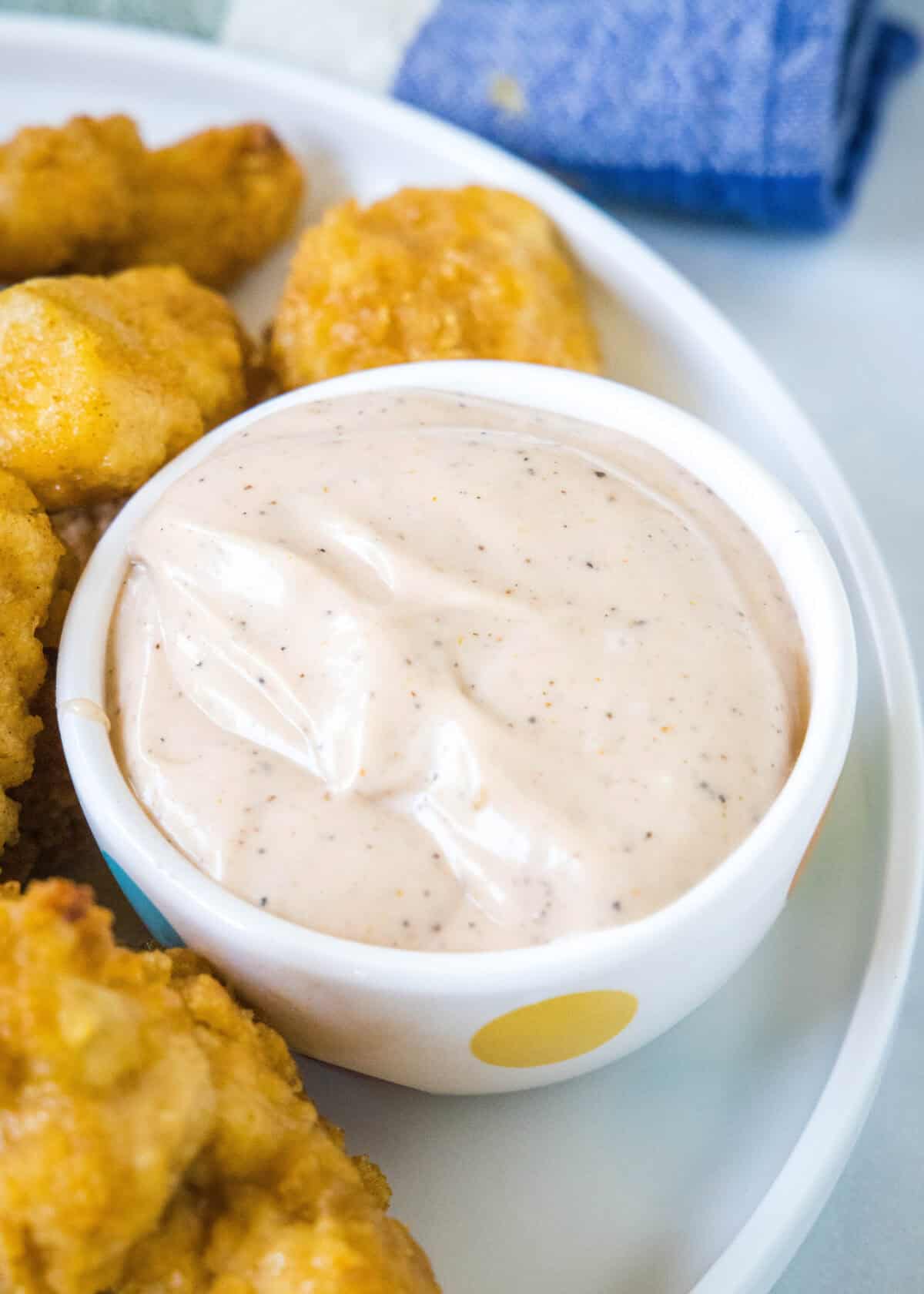 canes sauce in a bowl with chicken nuggets around it
