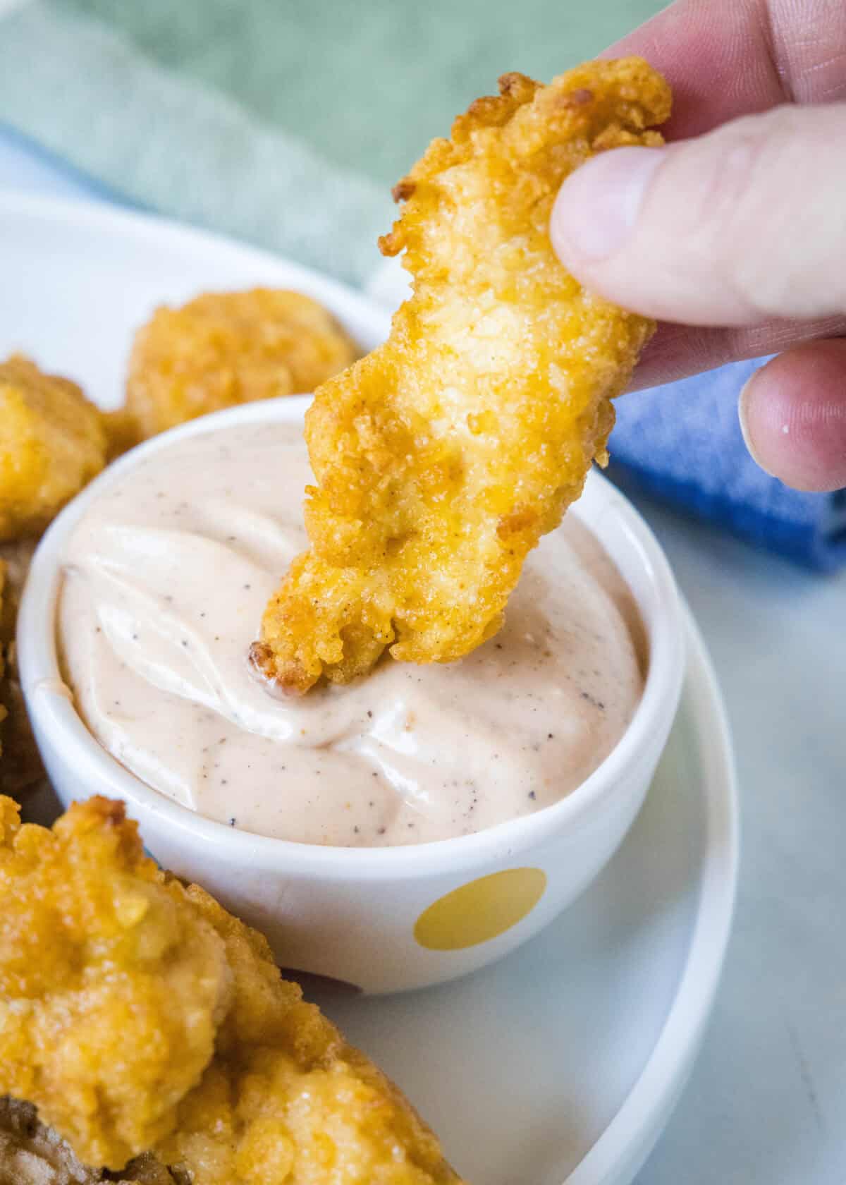 dipping chicken in canes sauce