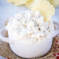 cropped square of caramelized onion dip in a white bowl with potato chips