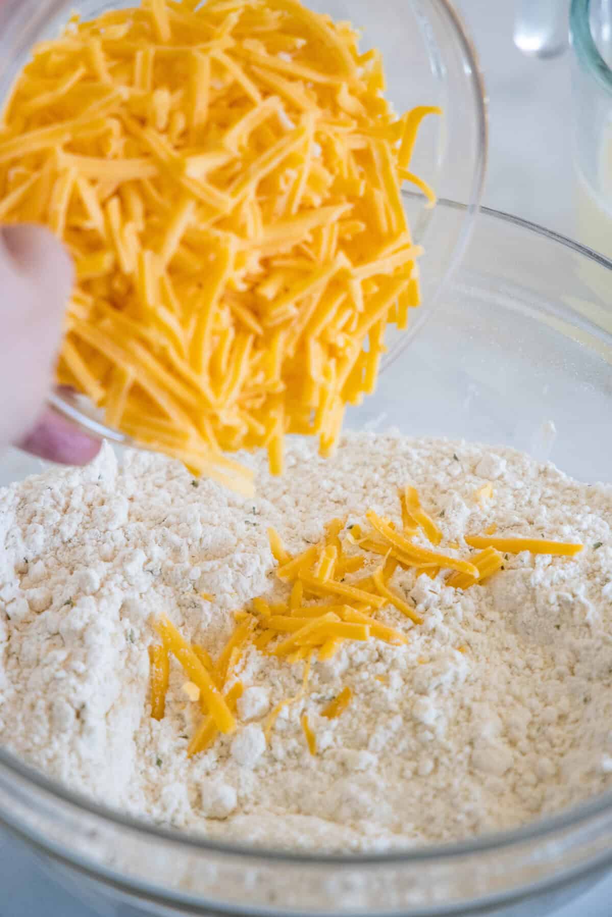 Shredded cheddar cheese added to a bowl with a buttery crumble.