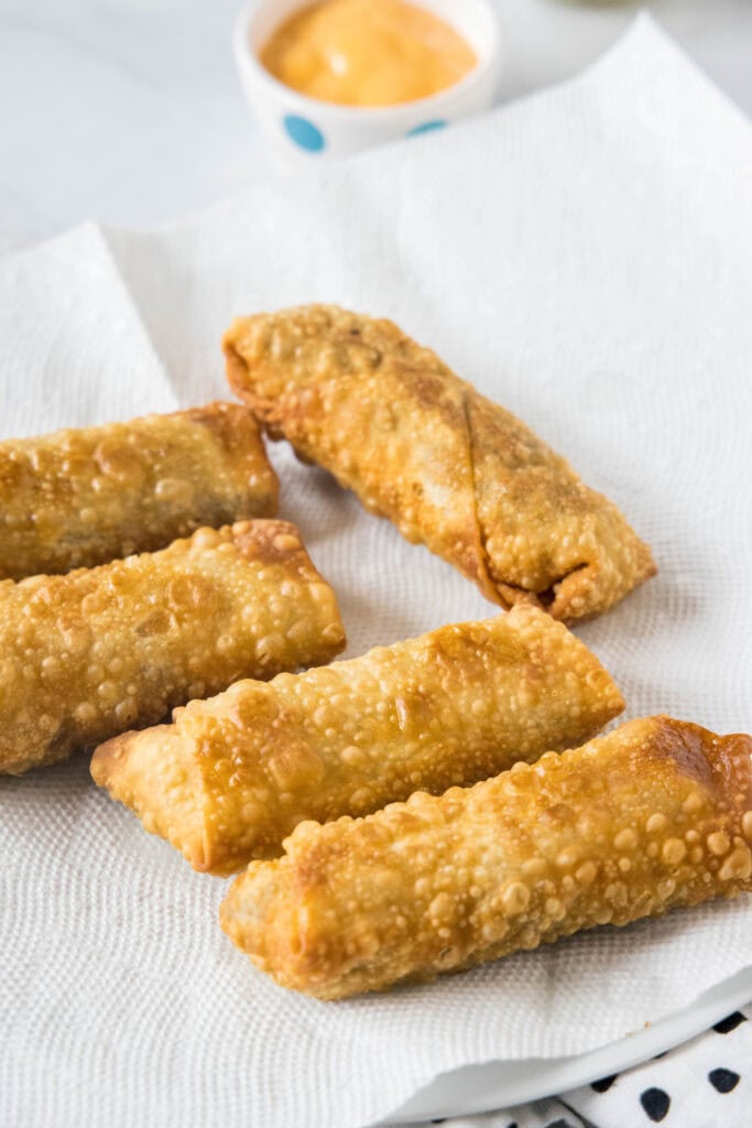 Deep fried cheeseburger egg rolls on a sheet of paper towel.