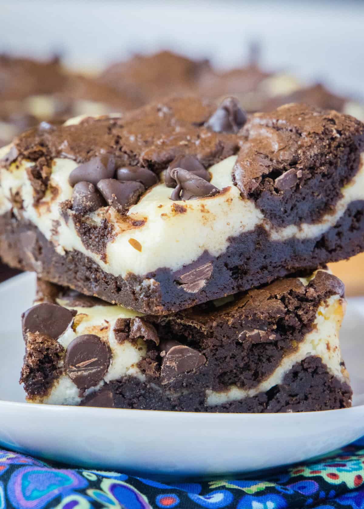 chocolate cheesecake brownies staked on a white plate