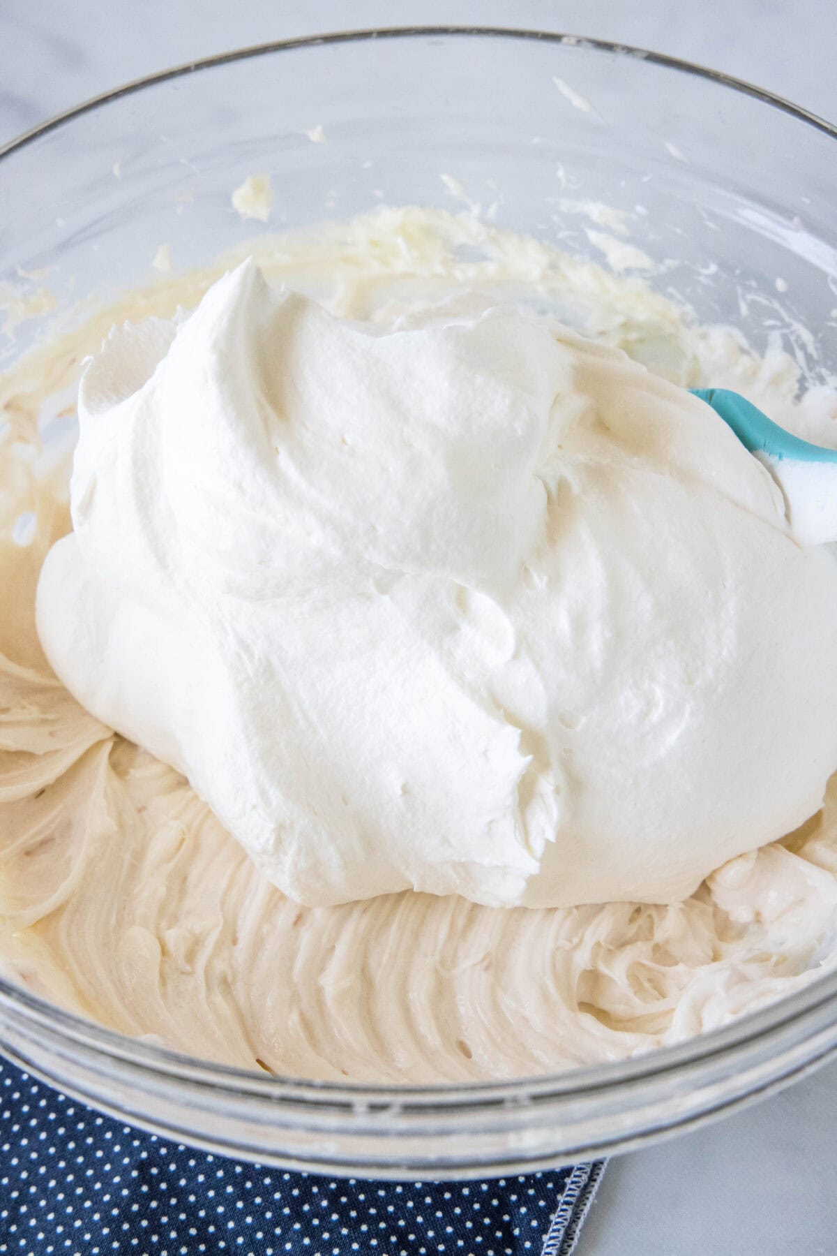Whipped cream added to a bowl of whipped cream cheese.