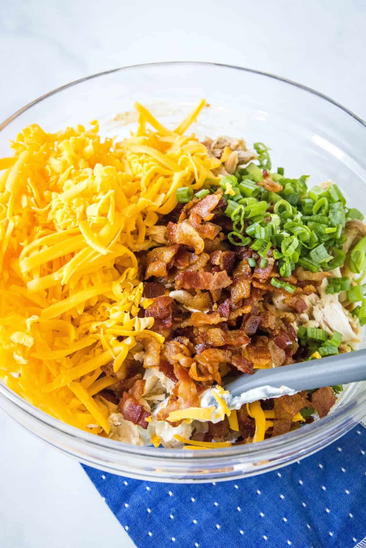 mixing cheese, bacon and green onions in a mixing bowl