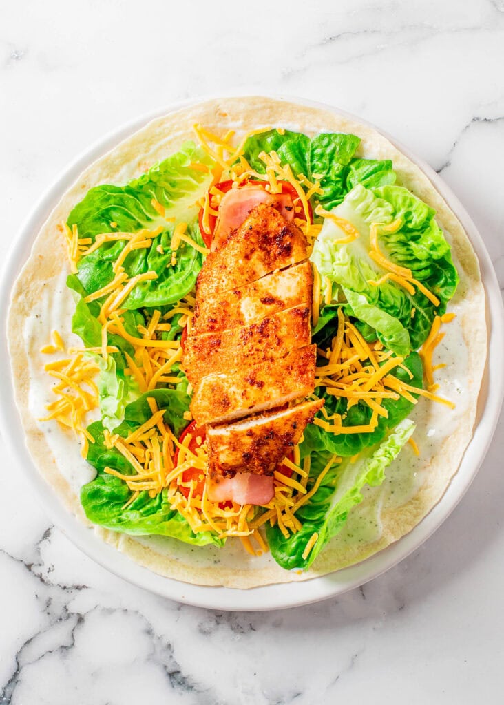 assembling chicken bacon ranch wrap on white plate