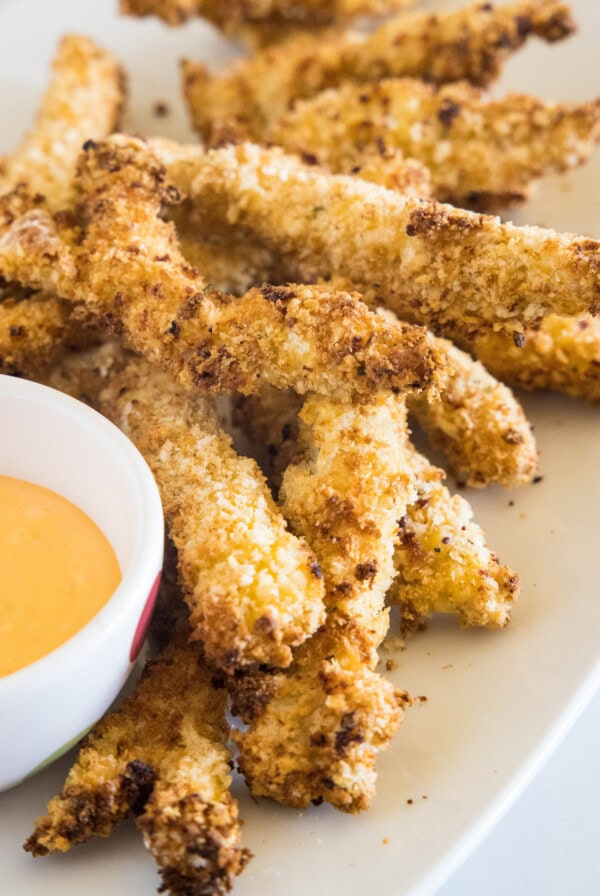 Chicken fries on an oval platter next to a bowl of dipping sauce.