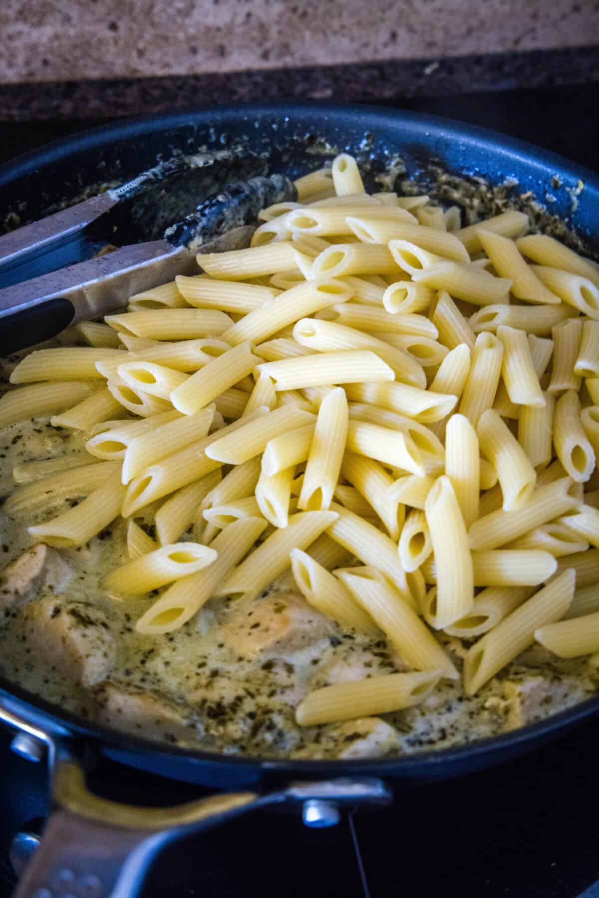 adding cooked pasta to skillet