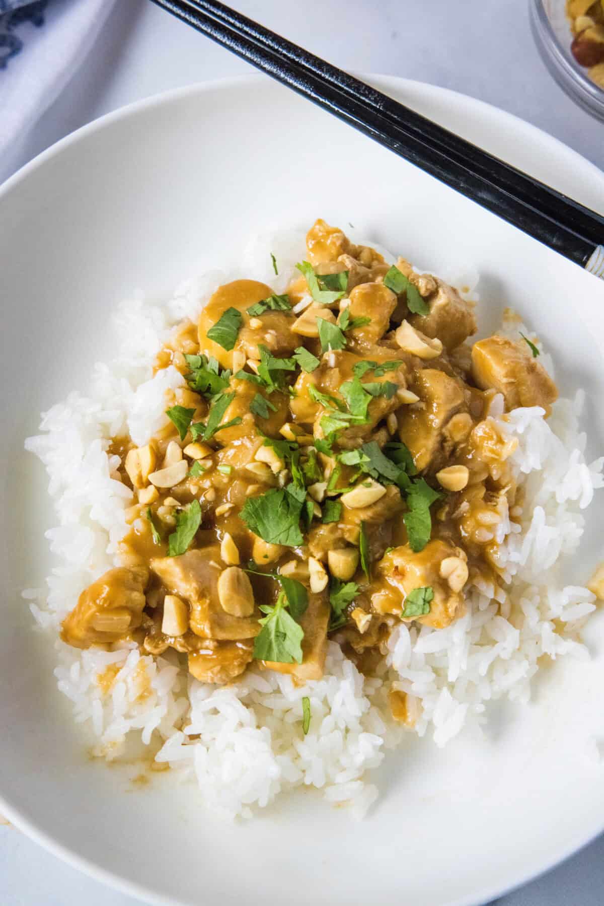 chicken satay stir fry over rice on a white plate