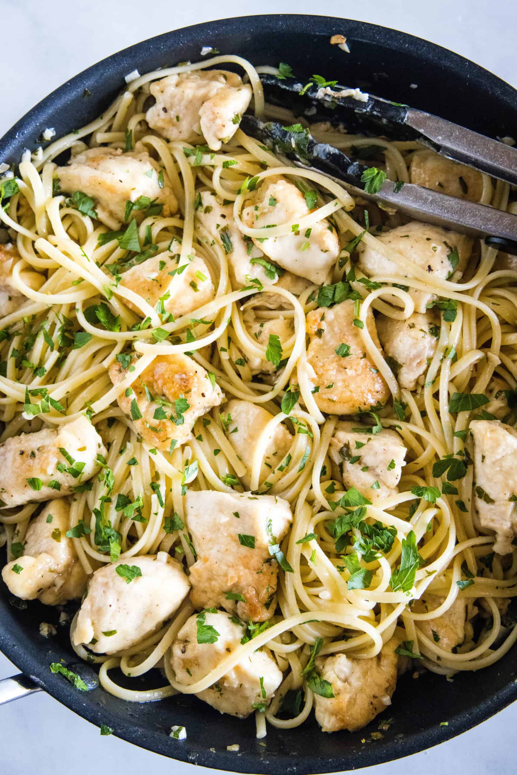Overhead view of chicken scampi with spaghetti in a skillet.