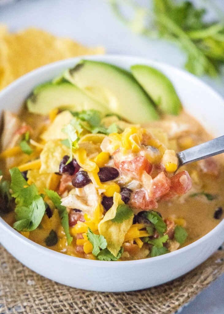 a spoonful of chicken taco soup coming out of the bowl