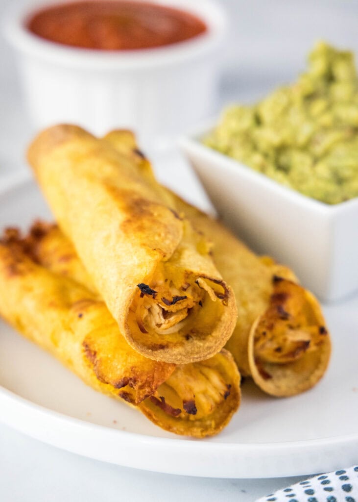3 chicken taquitos stacked on a plate