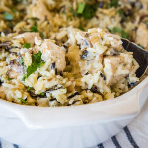 Close up of a spoon resting in chicken wild rice casserole.