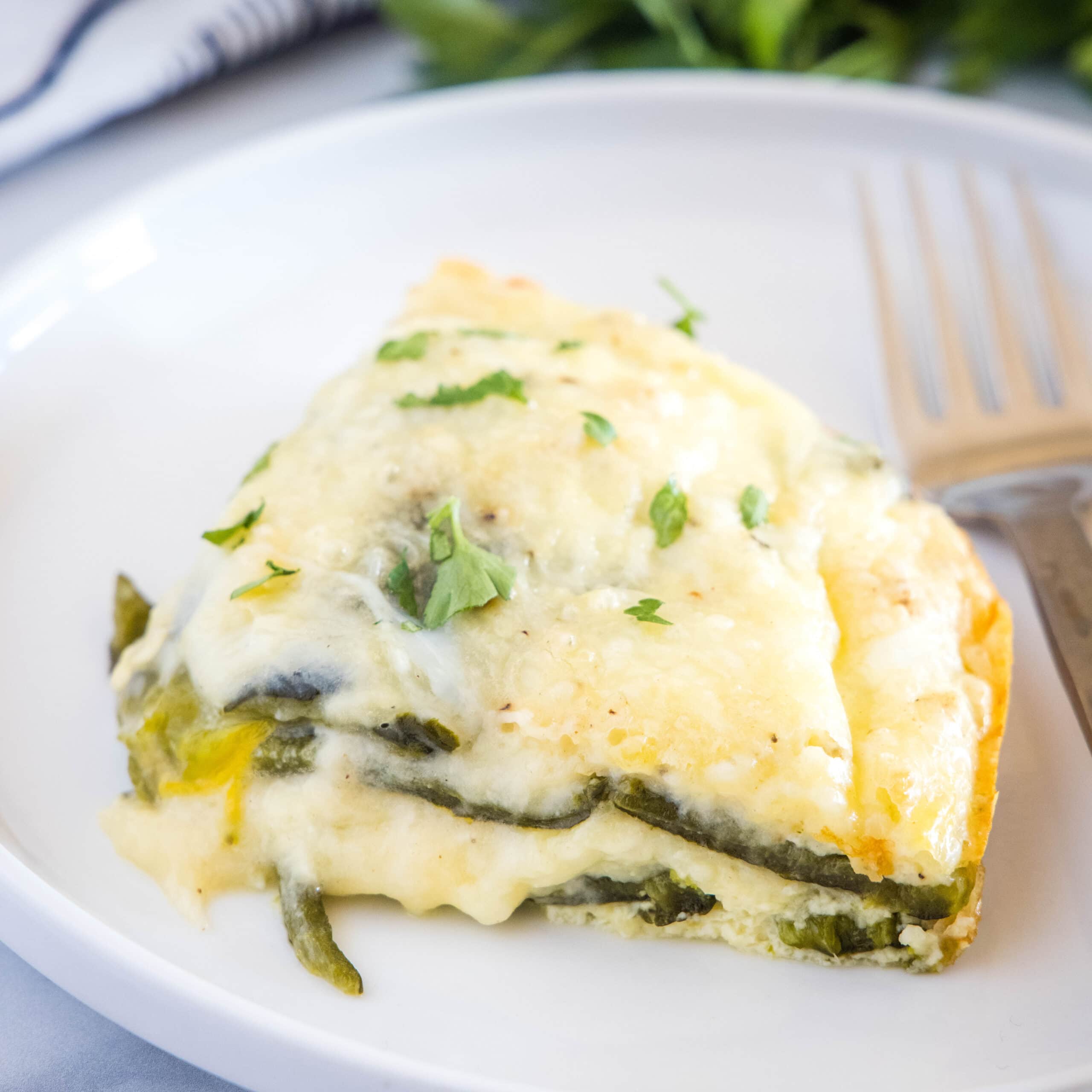 cropped close up of chili relleno casserole on a plate with a fork