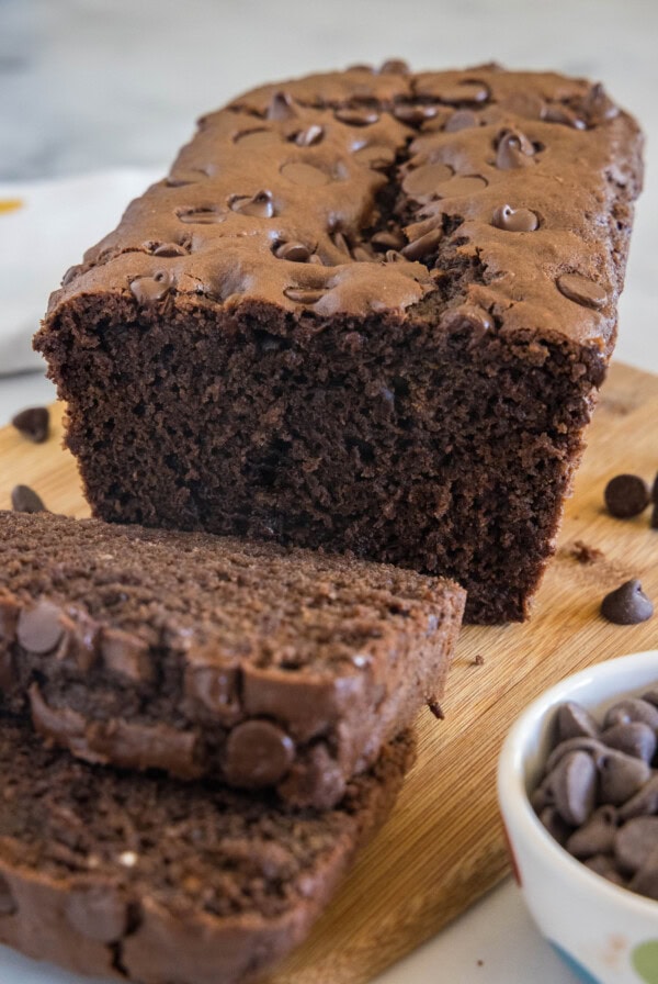 Chocolate bread with two slices cut from the end on a wooden cutting board.