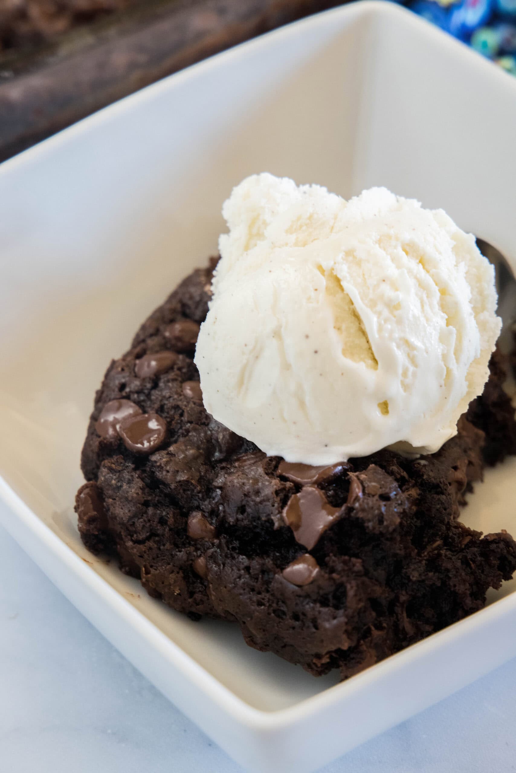 A slice of chocolate dump cake topped with a scoop of vanilla ice cream on a white plate.