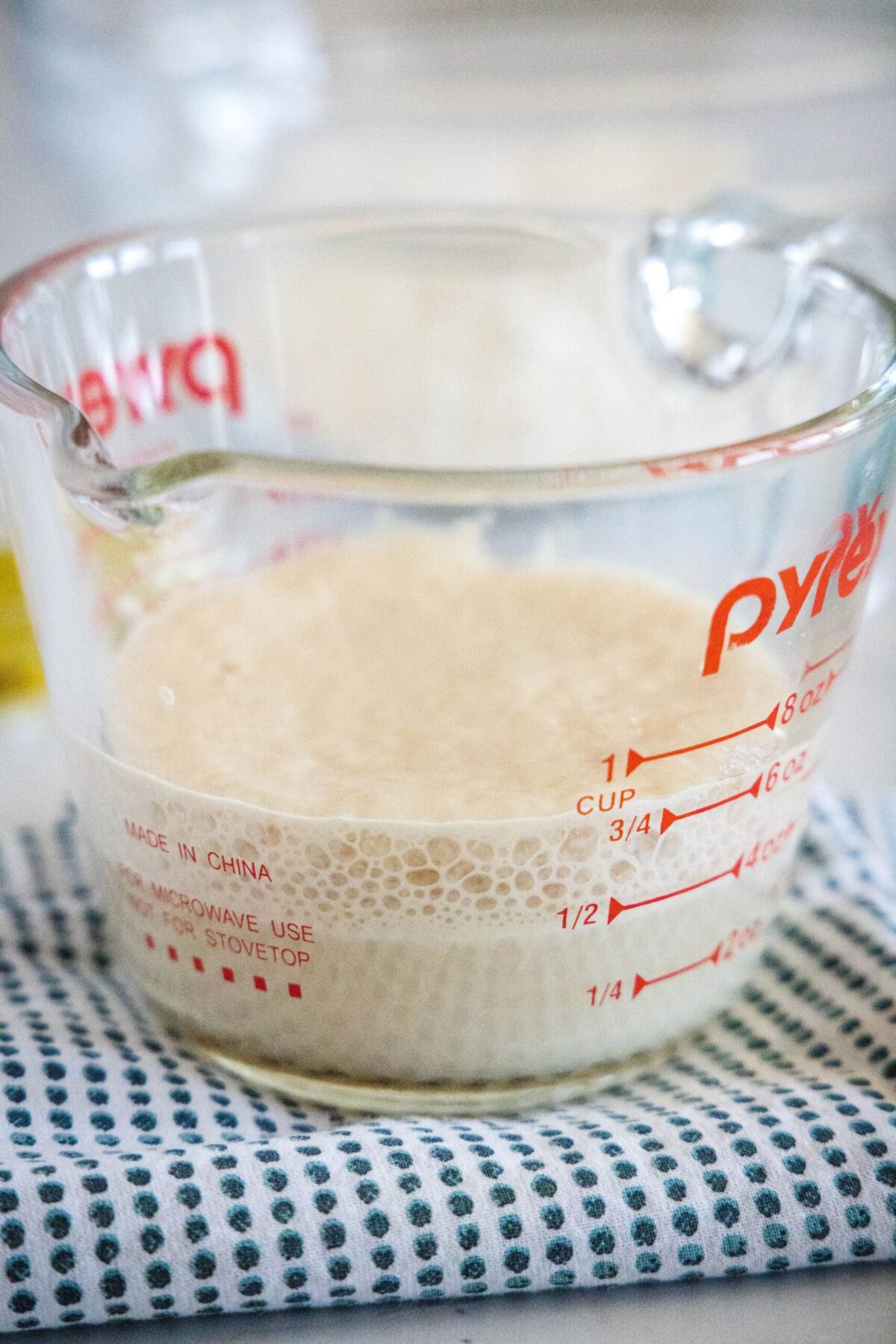 A pyrex container with yeast and water foaming in it