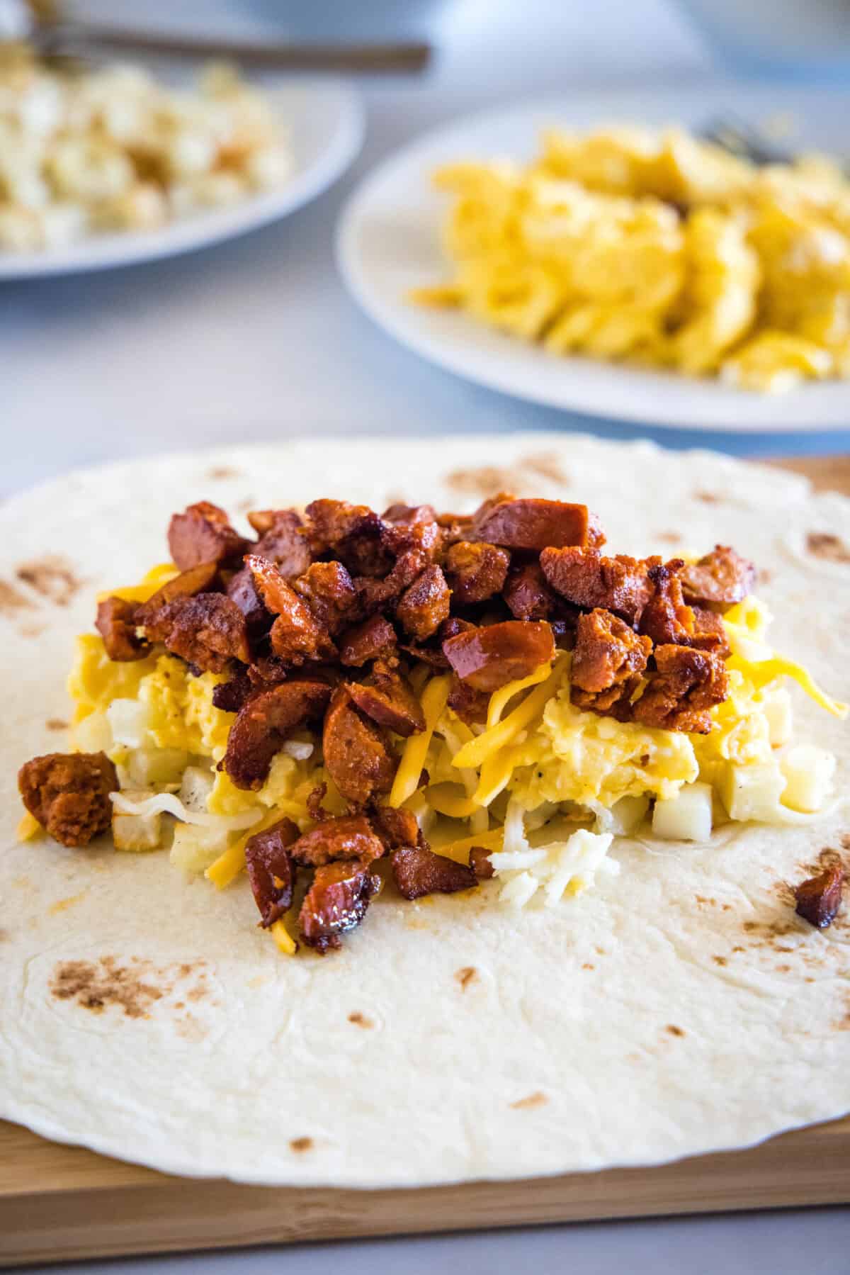 This chorizo breakfast burrito is a cheesy breakfast wrap loaded with crispy hash brown potatoes, spicy chorizo sausage, and fluffy eggs! A flour tortilla topped with hash brown potatoes, scrambled eggs, shredded cheese, and cooked chorizo.