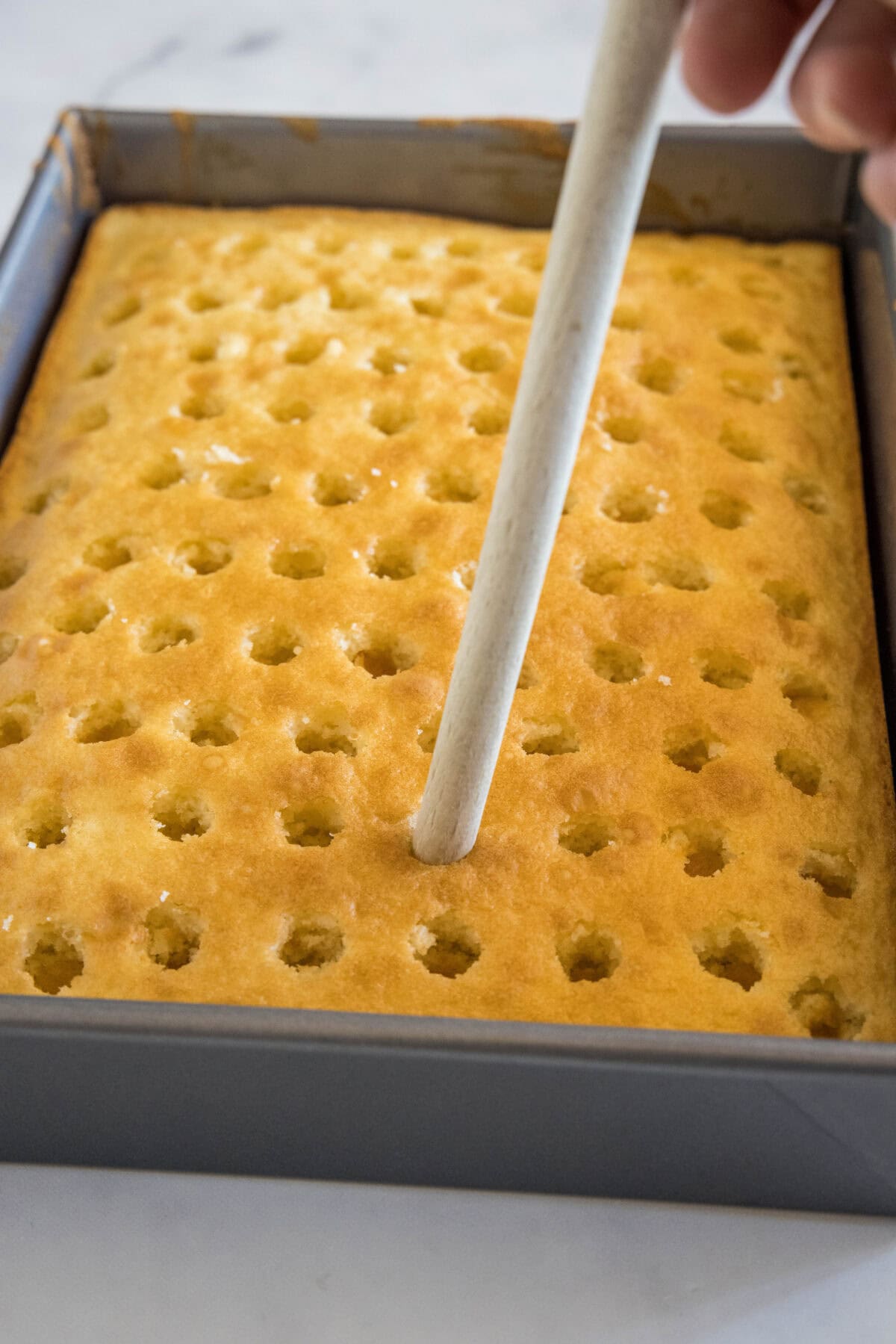 using wooden spoon to poke holes in hake