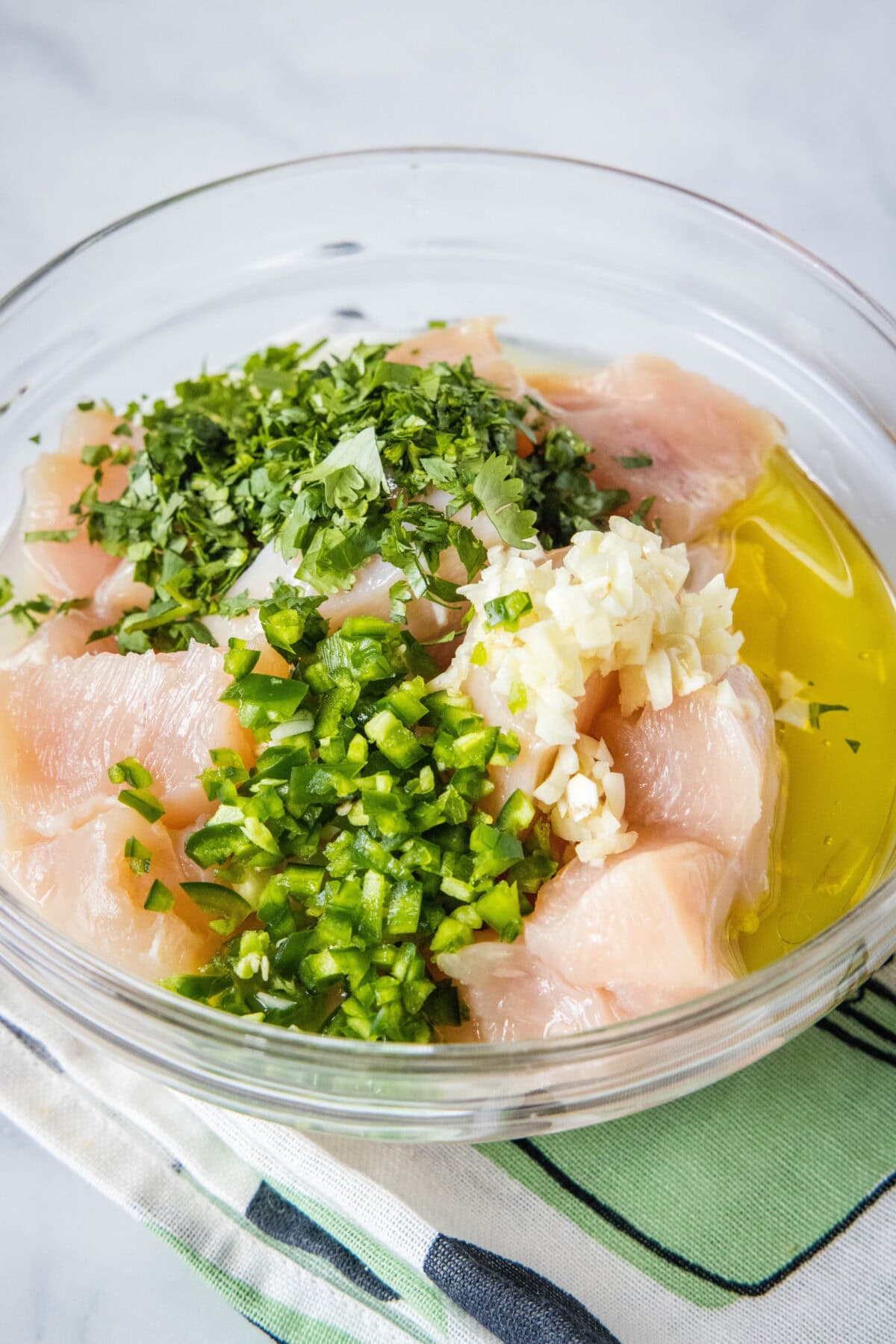 Chicken added to a bowl of cilantro lime marinade.