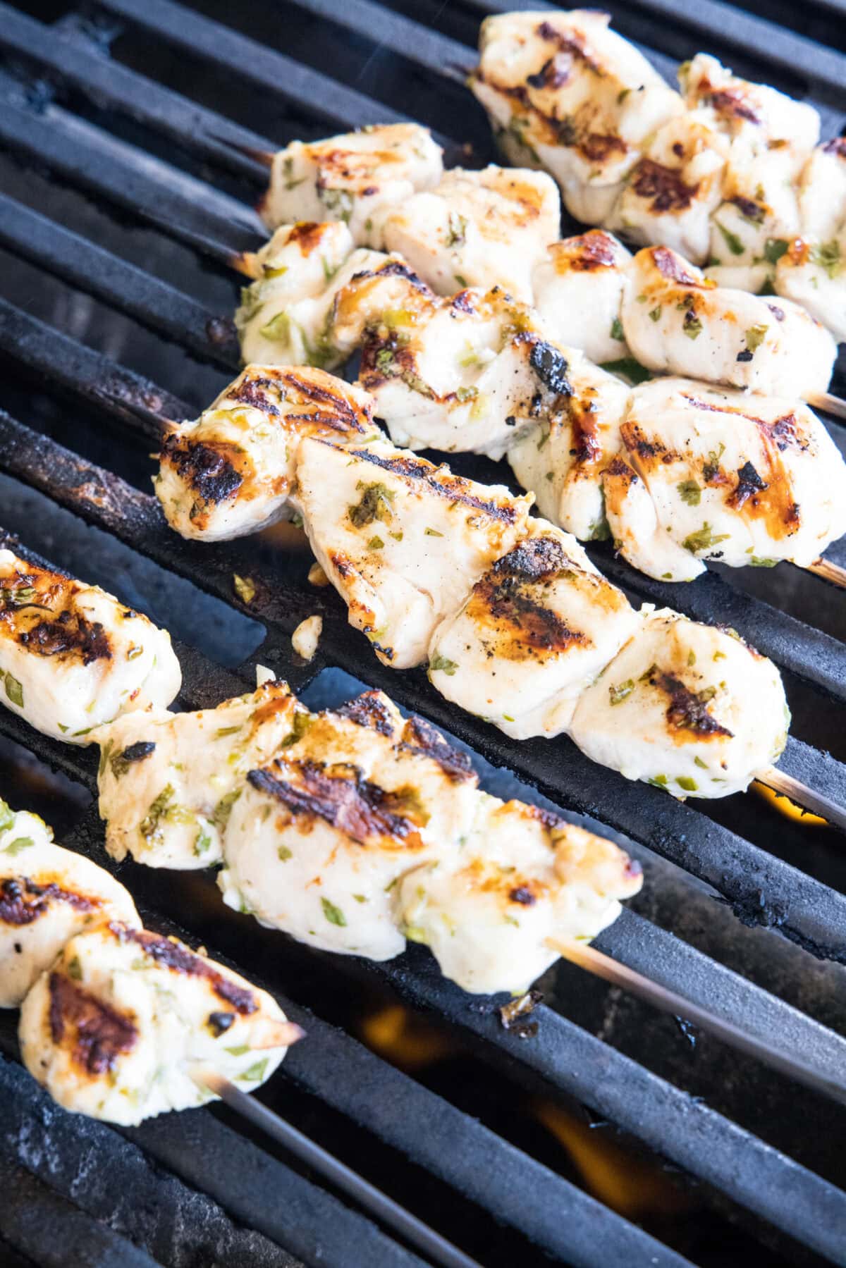 Cilantro lime chicken skewers cooking side by side on a hot grill.
