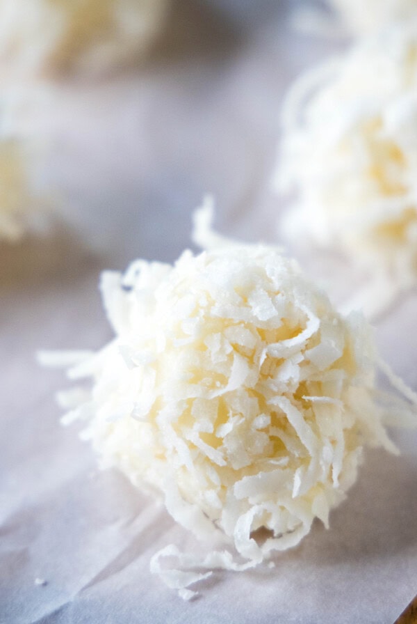 Close up of a white chocolate truffle topped with coconut next to others