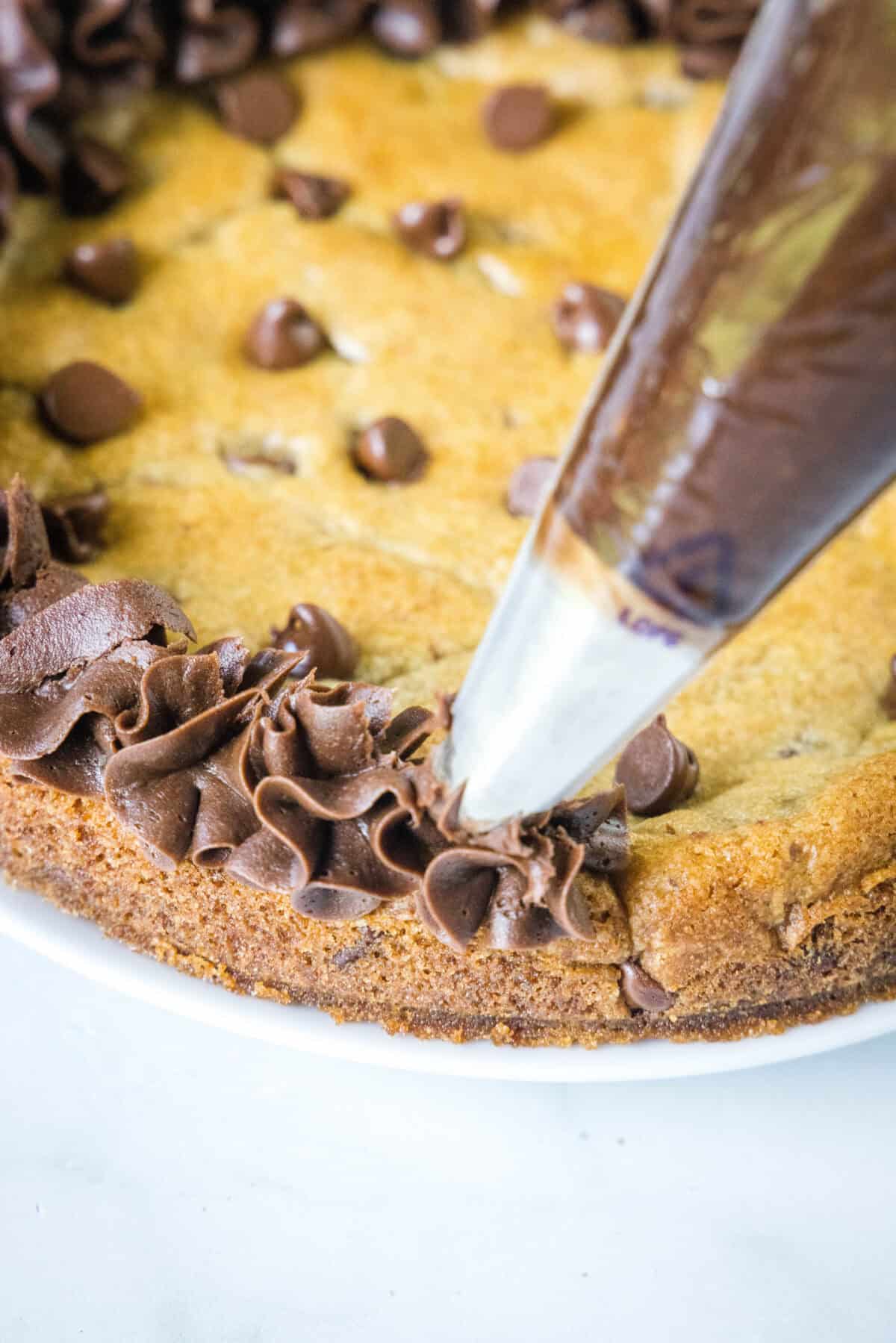 piping chocolate frosting onto a cookie cake