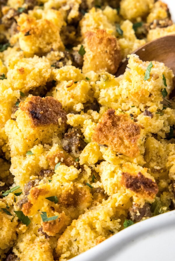 Close up of a wooden spoon in a casserole dish of stuffing