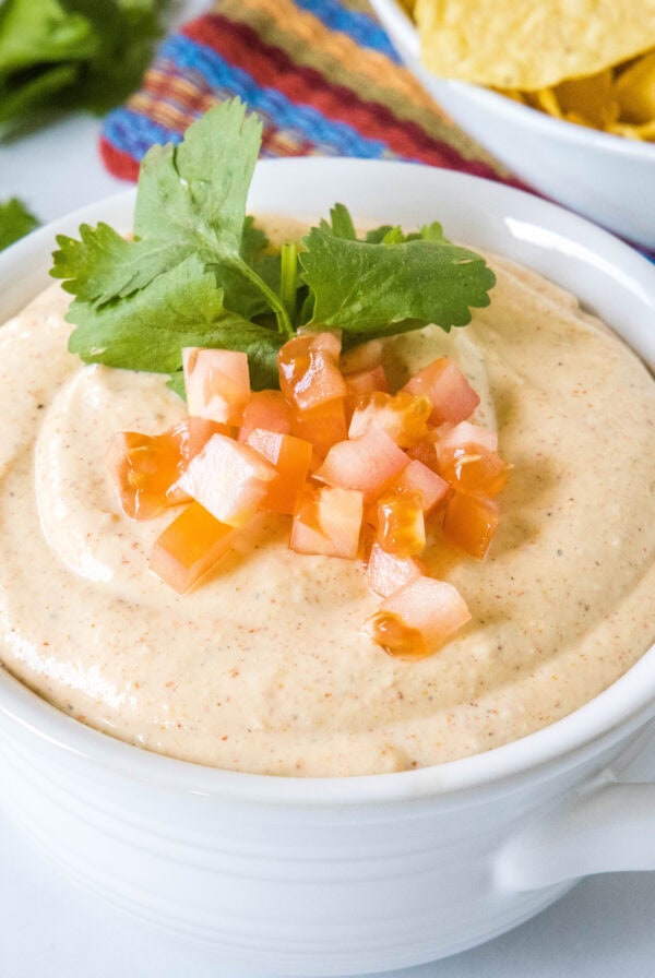 close up cottage cheese queso topped with tomatoes and cilantro