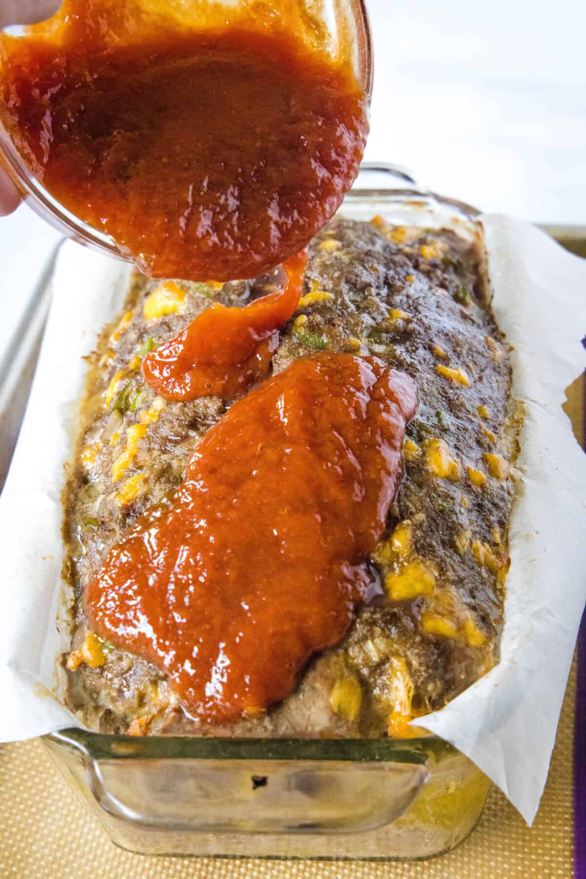 pouring glaze over meatloaf in loaf pan