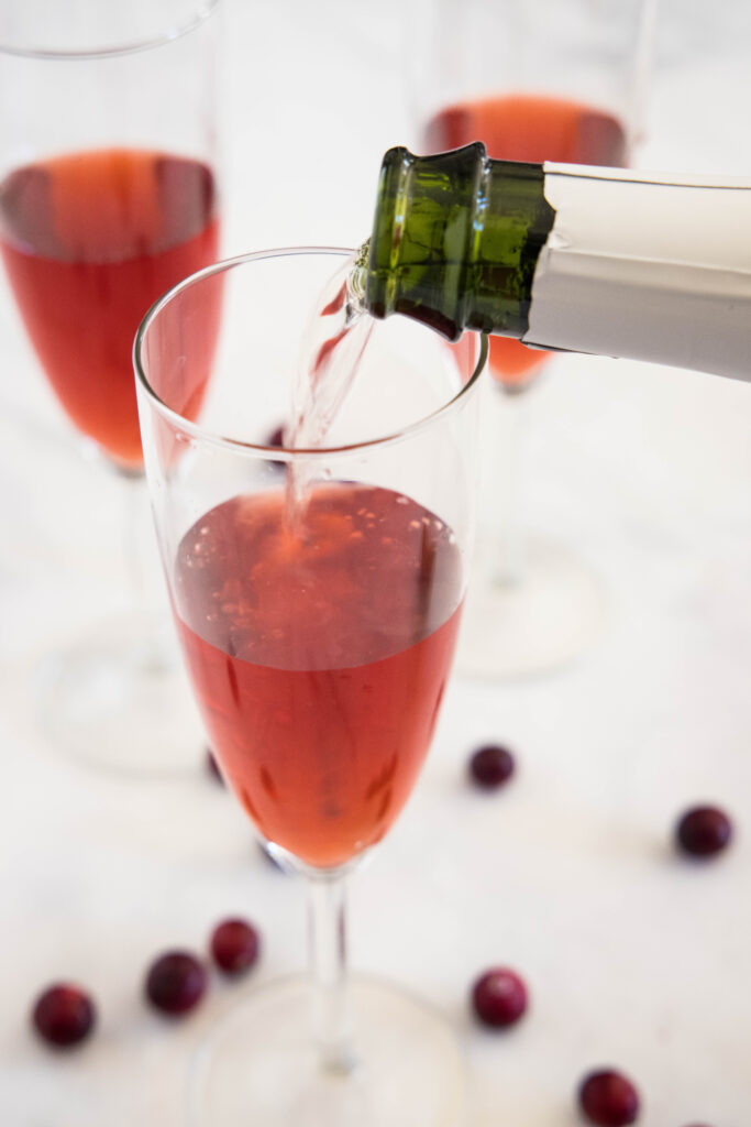 pouring sparkling wine into a glass with cranberry juice