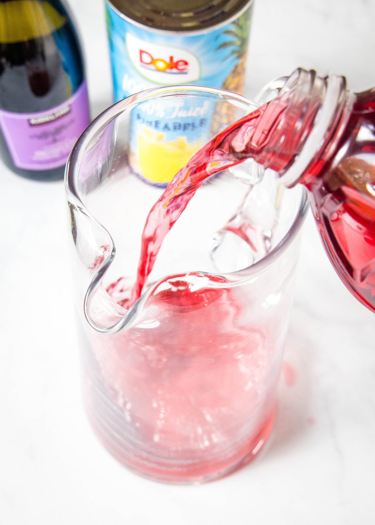 pouring cranberry juice into a pitcher