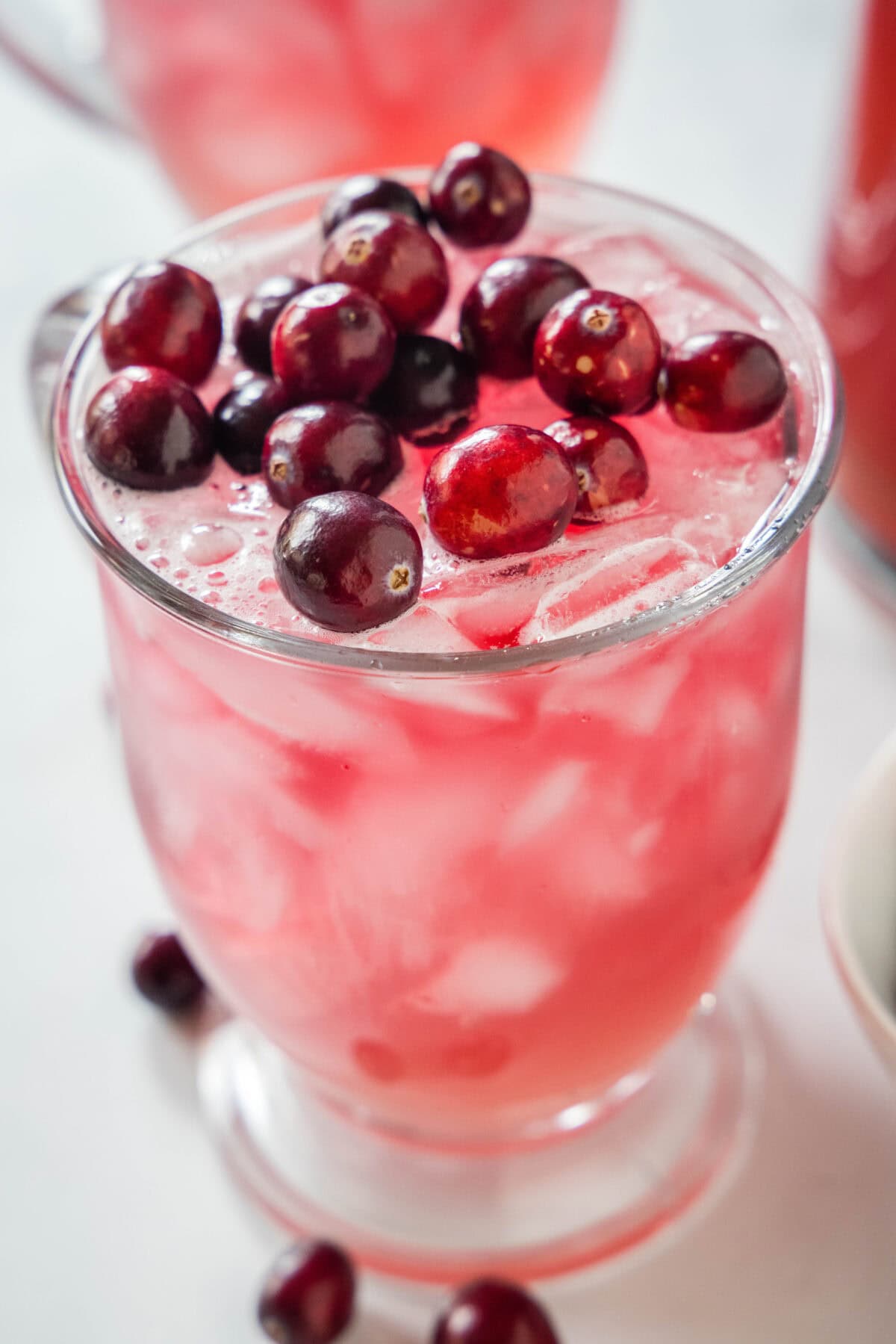cranberry punch in a glass topped with fresh cranberries