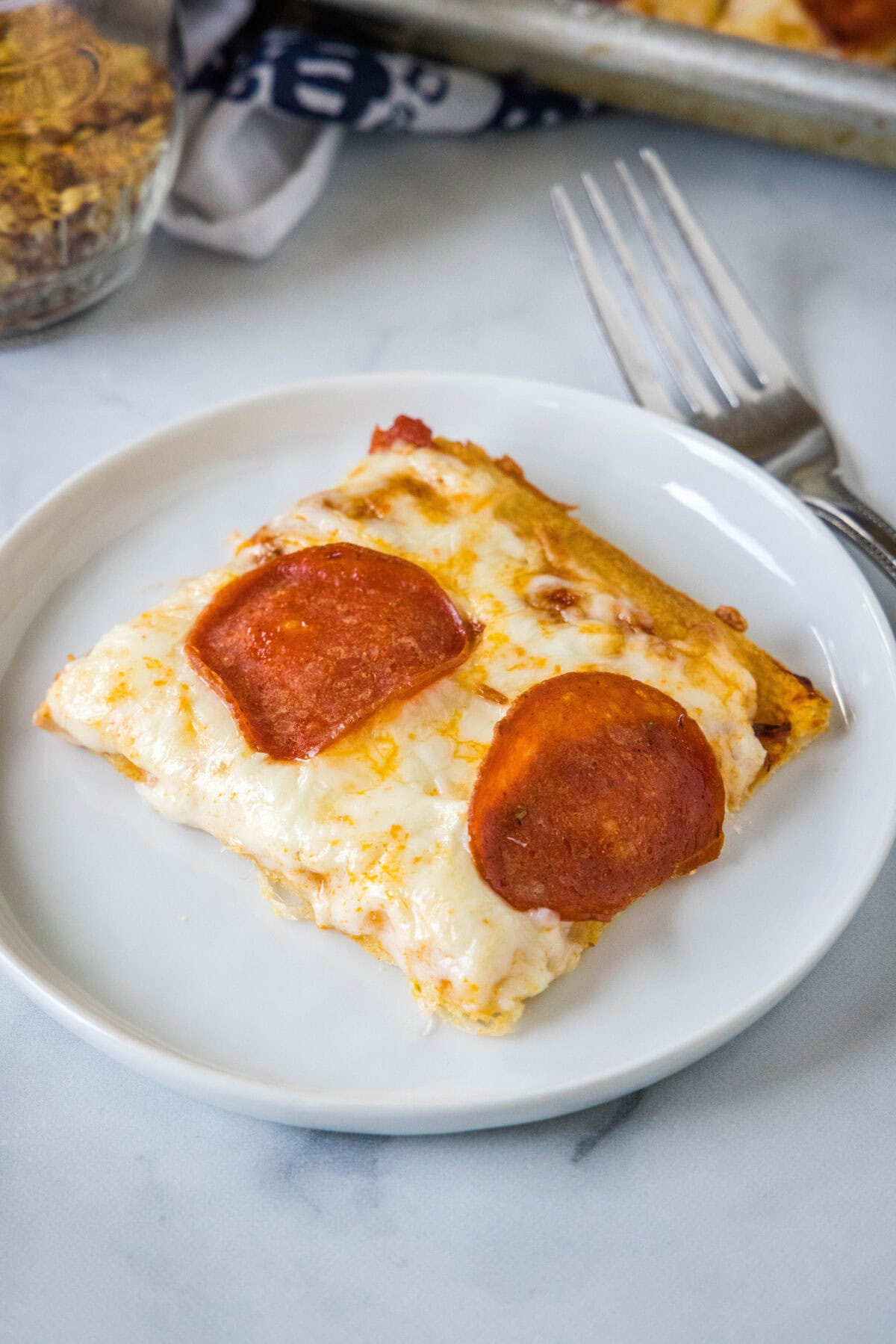 A slice of pepperoni crescent roll pizza on a white plate.