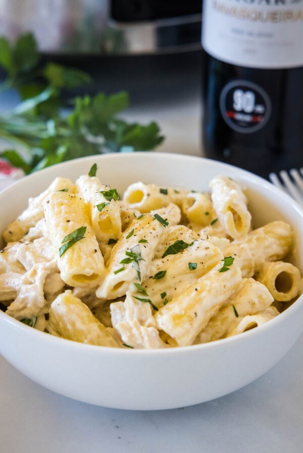 Crock pot chicken alfredo served in a white bowl.