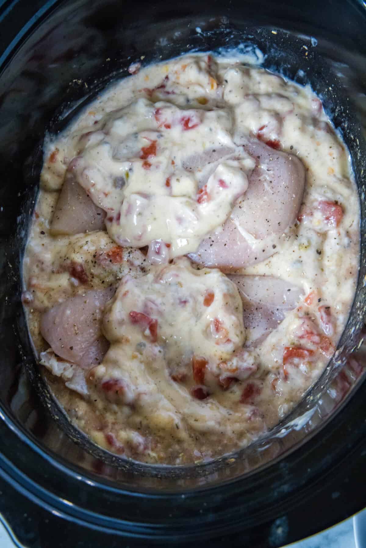 chicken spaghetti sauce ingredients in slow cooker with the chicken