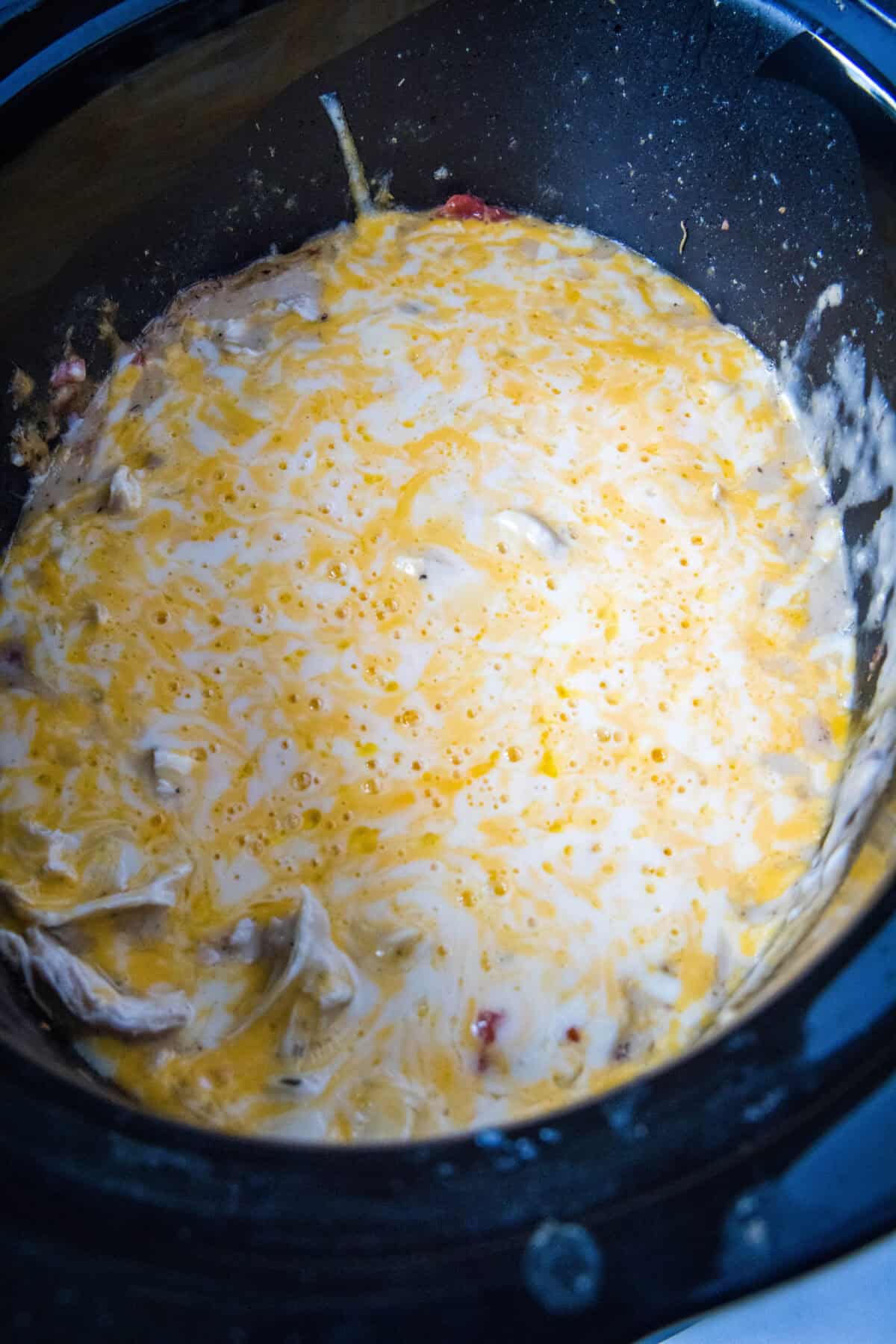 melted cheese and shredded chicken in crockpot