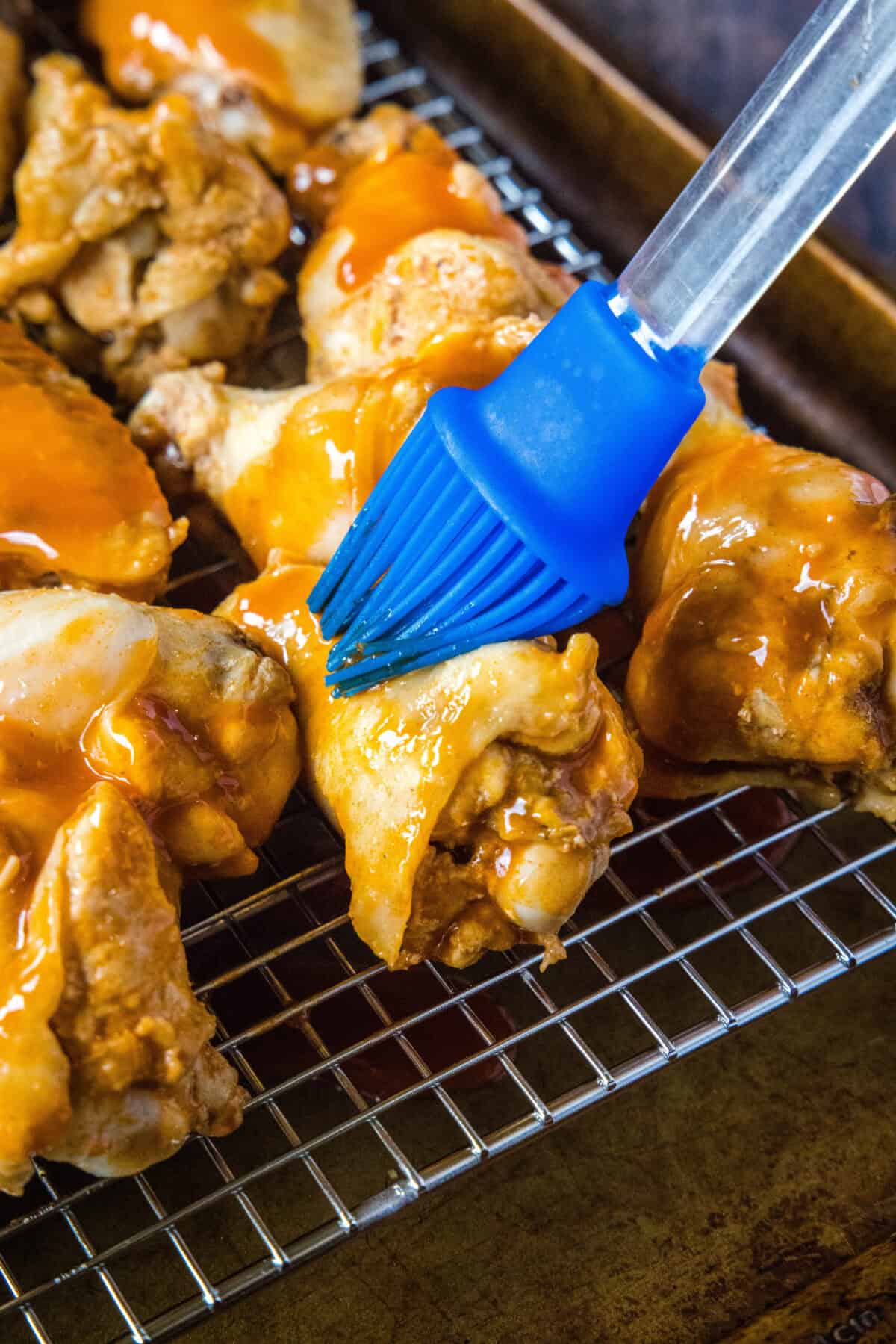 brushing sauce on chicken wings