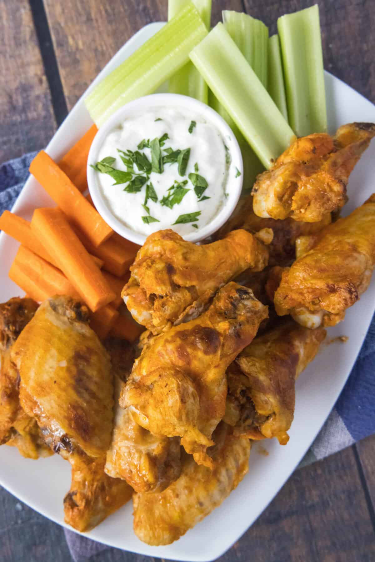 looking down on a plate of chicken wings with carrots and celery
