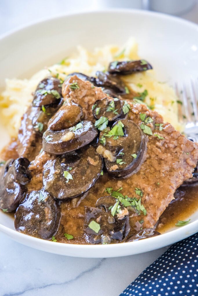crockpot cube steak on a plate with mushroom gravy