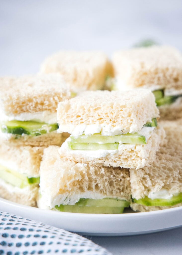 cucumber sandwiches stacked on a white plate