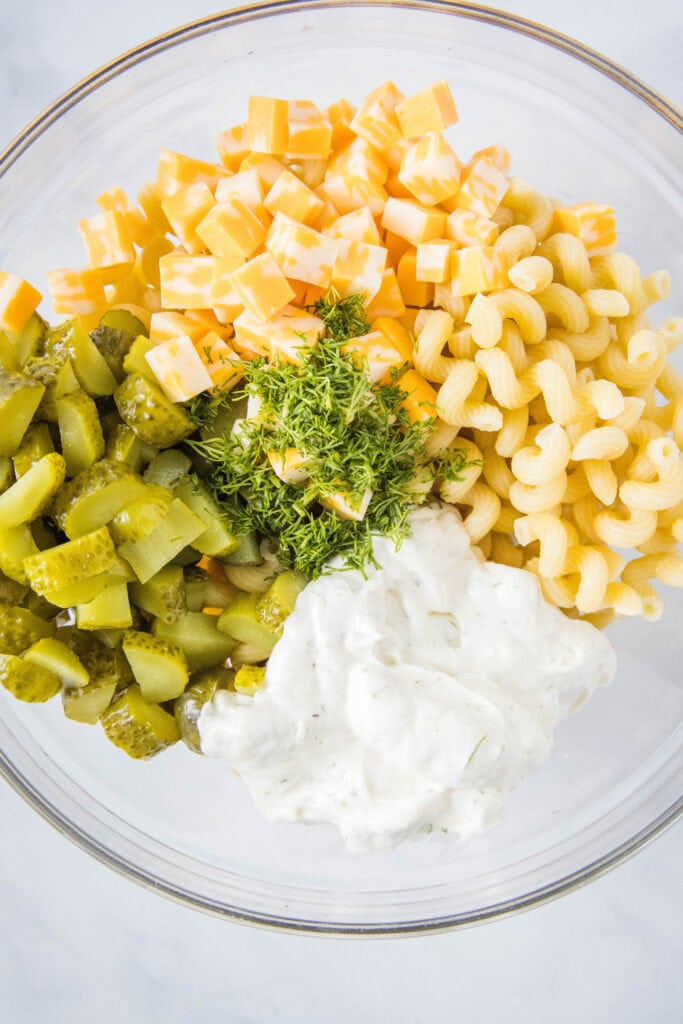 mixing pickle pasta salad together in a bowl