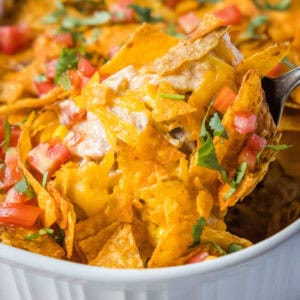 scooping dorito chicken casserole out of dish