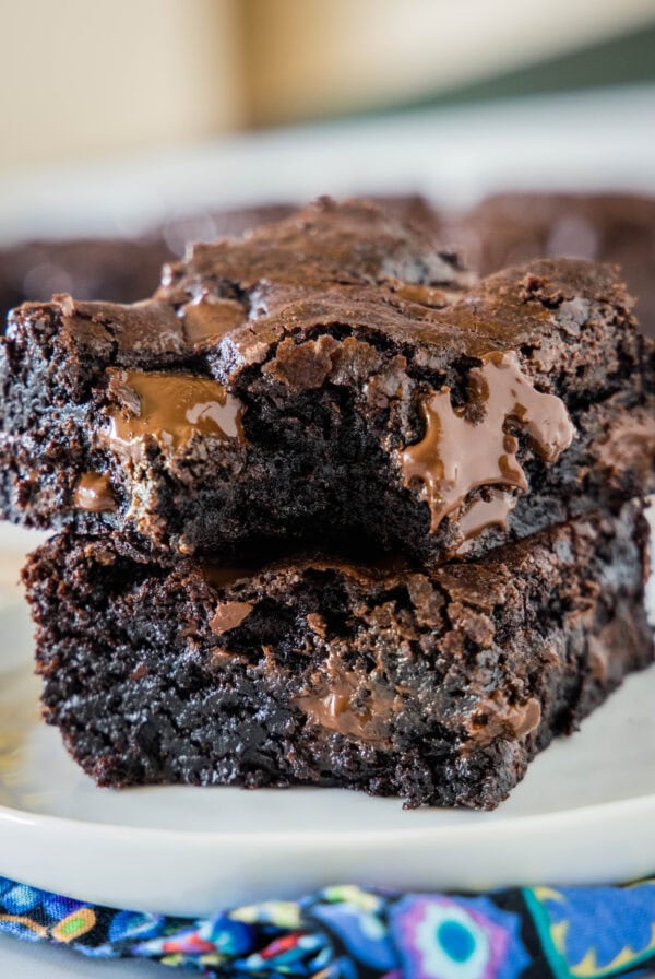 Two double chocolate brownies stacked on a plate with a bite missing from the top brownie.
