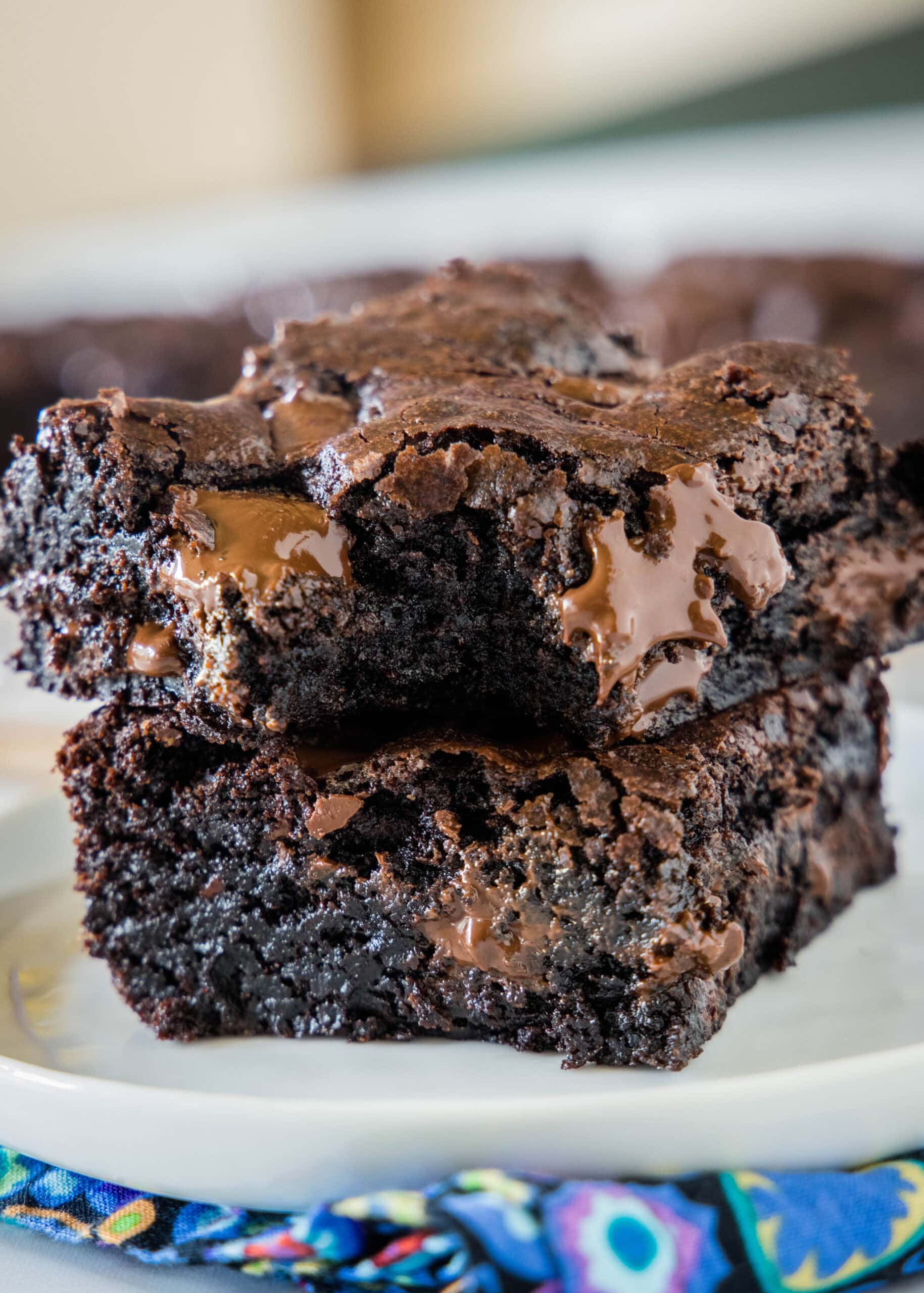 Two double chocolate brownies stacked on a plate with a bite missing from the top brownie.