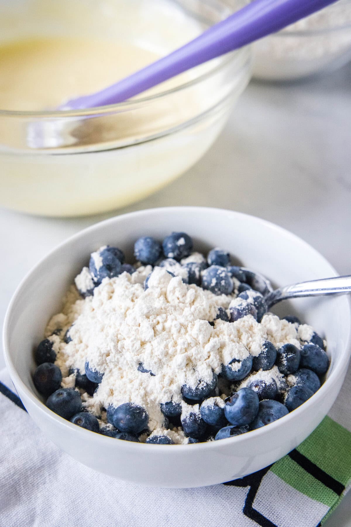 adding flour to blueberries