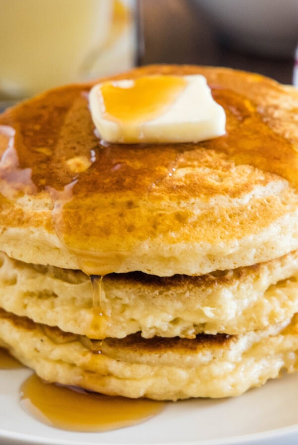 close up stack of eggnog pancakeson a white plate