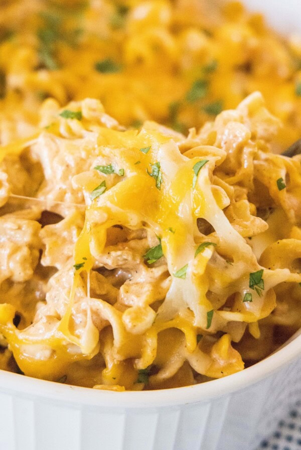 close up scooping chicken pastas out of baking dish